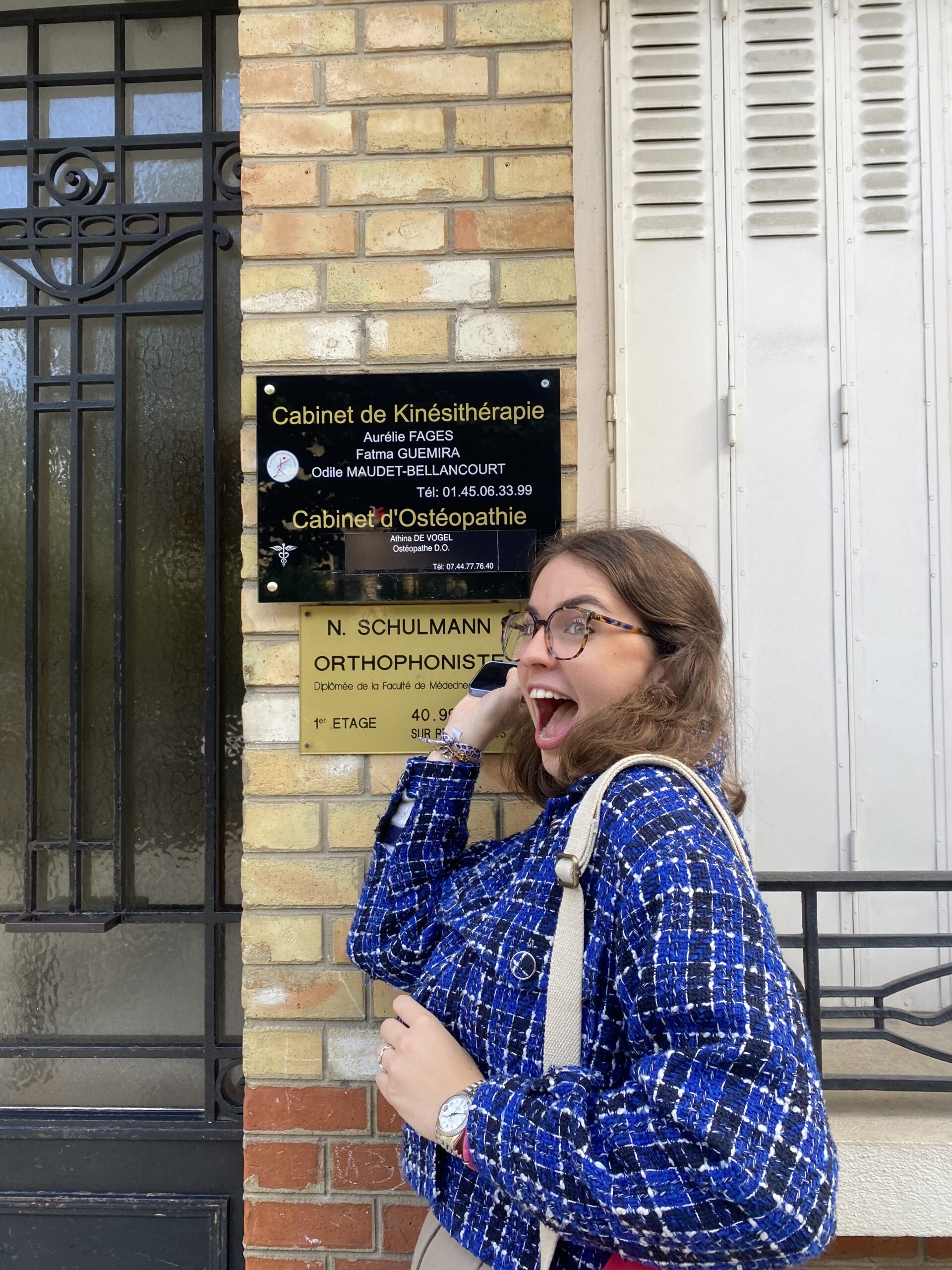 Athina de Vogel devant la plaque du cabinet rue Berthelot à Suresnes