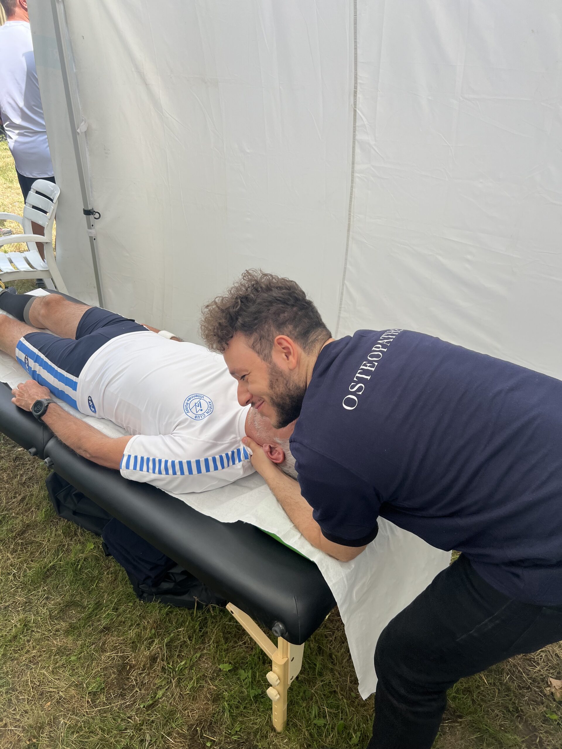 Ostéopathe qui manipule un joueur de rugby avec le sourire