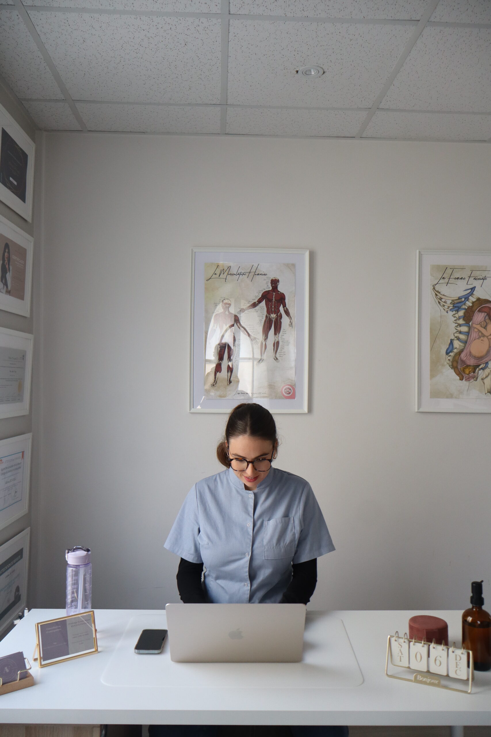 Bureau de cabinet d'ostéopathie, avec ordinateur et éléments anatomiques.