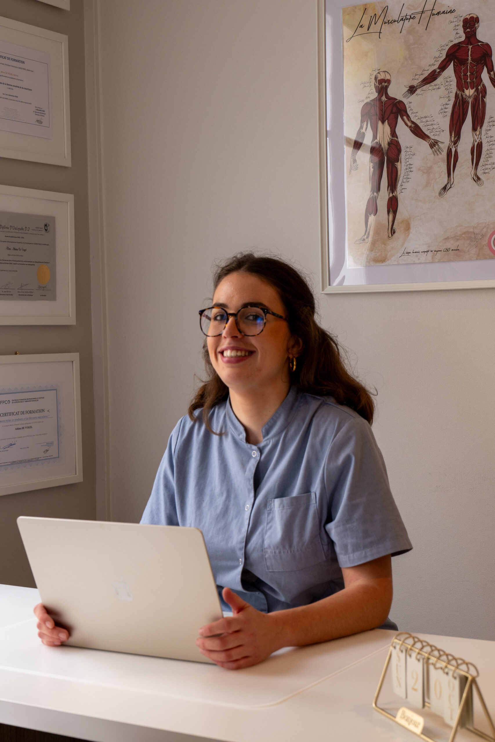 athina de vogel assise au bureau avec ordinateur et sourire - qu'est-ce que la cohérence cardiaque ? - pratiquer la cohérence cardiaque au quotidien : guide pratique